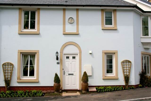 A pale blue house with tan and trim and a bright white door