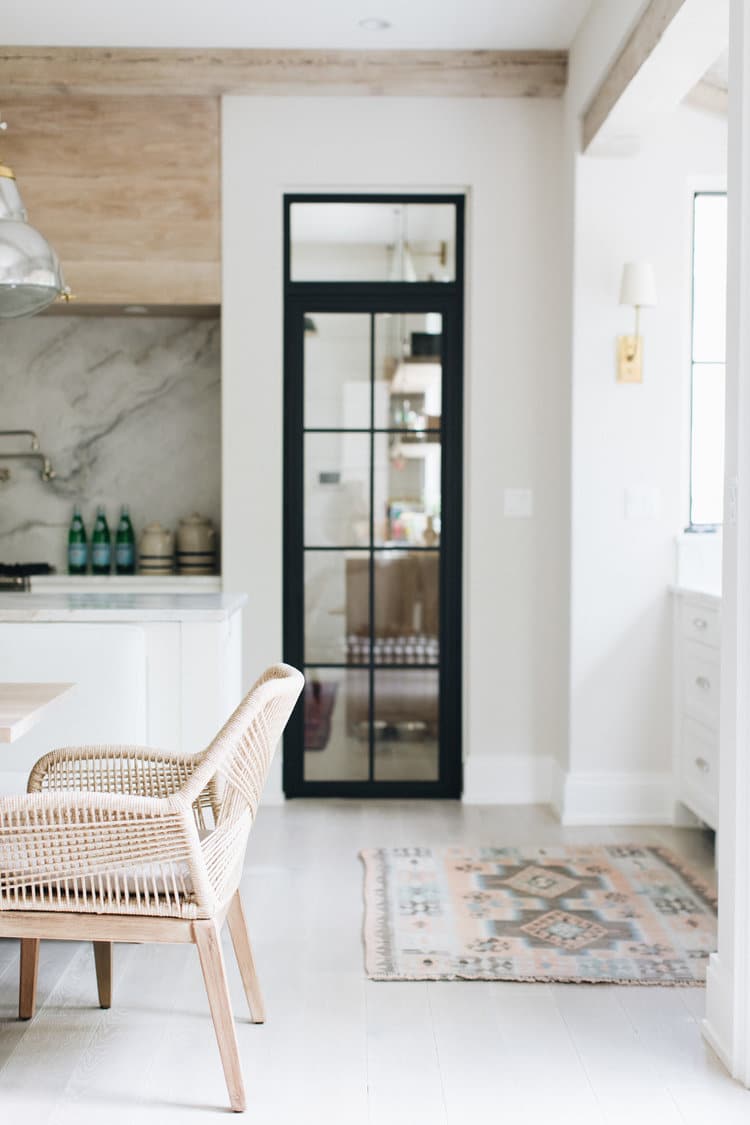 Alt tag for white-modern-open-kitchen-steel-door-marble-sink-slab-backsplash-woven-dining-room-chairs-cococozy-katemarkerinteriors