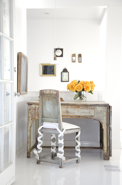 home office with reclaimed wood desk and chair with an orange flower arrangement in a glass vase