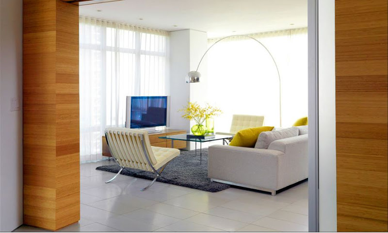 Modern living room with lots of mid-century modern pieces (Barcelona leather chairs and Arco floor lamp), a boxy sofa, monochromatic grey rug, yellow accent pillows and large floor length windows covered with sheer curtains