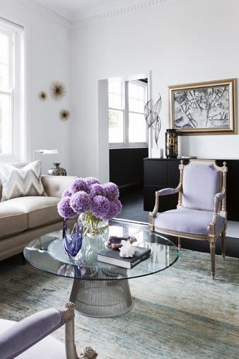 Contemporary living room with lavender Louis XIV chairs, a Saarinen inspired coffee table with a glass top and purple hydrangenas