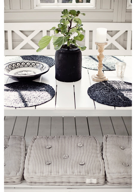 Table setting on a grey front porch with stripped pillows and Moroccan inspired bowls