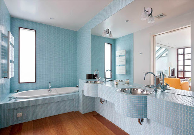 bathroom with wood floor but the walls, appliances (step in tub, sink, counter) are covered in light blue tiles