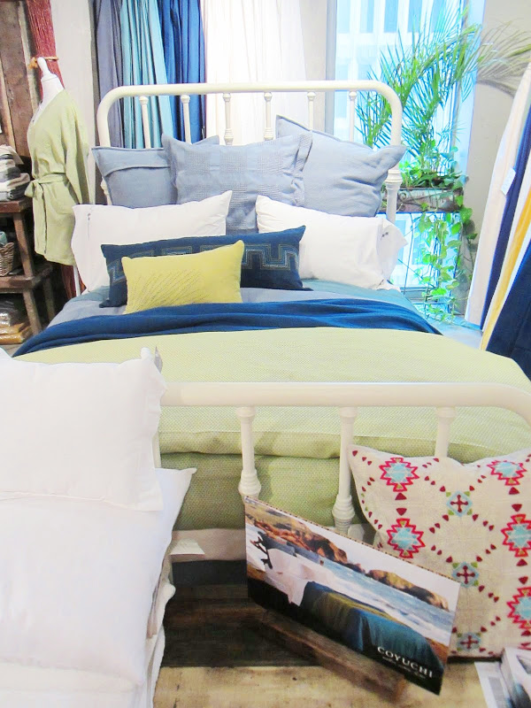 Bed with white iron frame and blue, white and green pillows and sheets