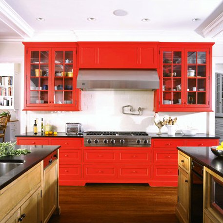Kitchen with black counter tops, bright red drawers and cabinets and stainless appliances