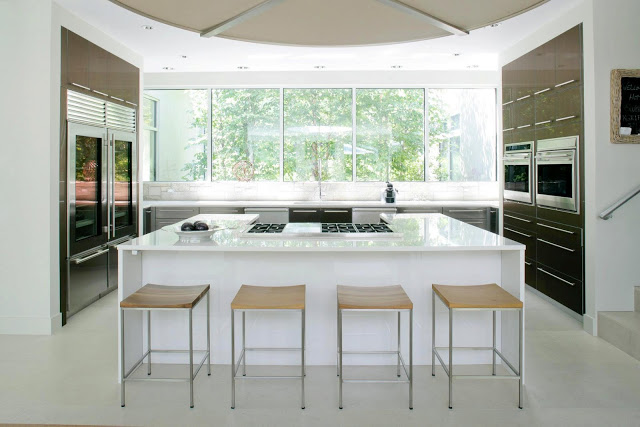 White kitchen in a modern farmhouse with wooden cabinets with long drawer pulls, a large white island and a large window