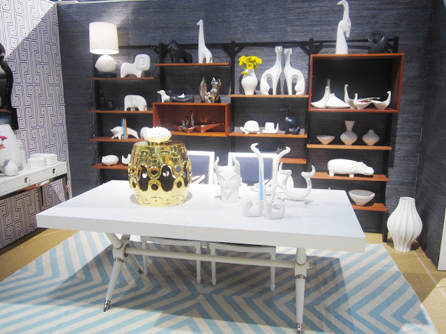 white dining table with lots of small sculptures and candle stick holders on light blue chevron rug at Jonathan Adler's nyigf booth