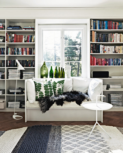 Home library white bench built in bookshelves green bottles grey rug herringbone wood floor