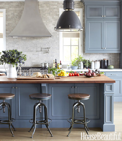 kitchen with black pendant lights, blue grey cabinets, turn stools, butcher island and tumbled marble backsplash