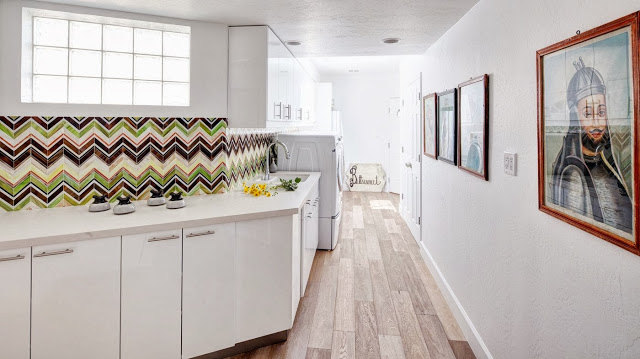 Angled wall in a laundry room with green, brown and white chevron printed backsplash