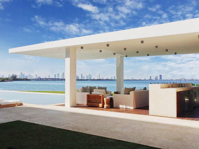 view of Miami skyline from the outdoor bar lounge area with white sofas and wood floor