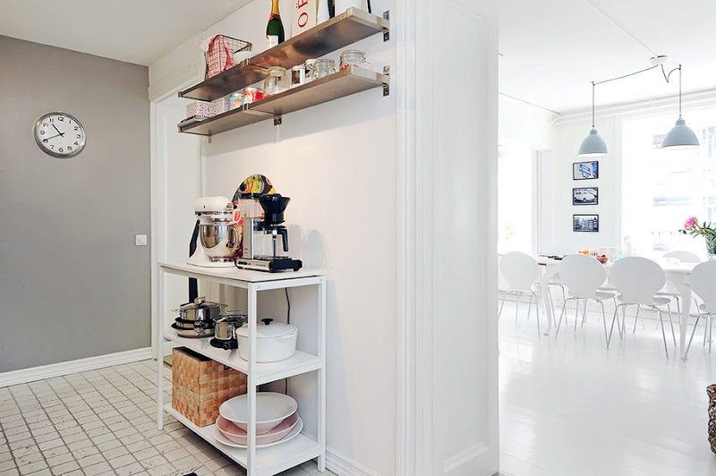 Small kitchen with floating shelves, grey walls, white tile floor and a view of the dining room