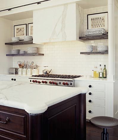 kitchen with a marble slab range hood cover, subway tile backsplash, black drawer pulls, an industrial stool and a wood island