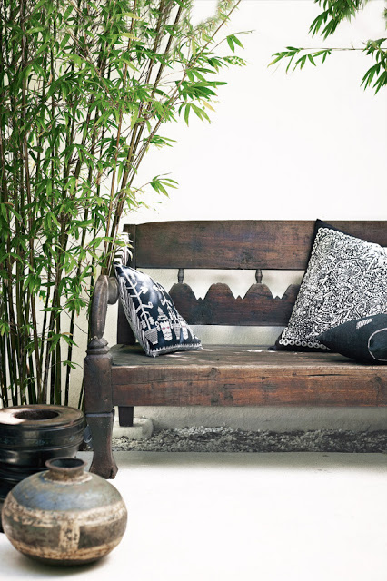 Patio with outdoor bench, navy blue and white pillows, bamboo, and two bowls