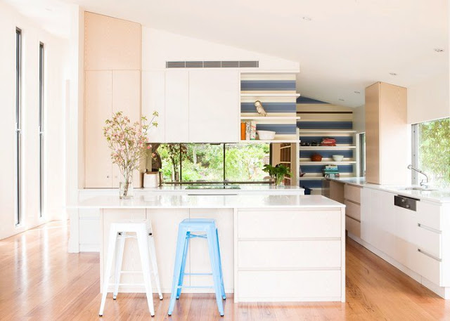 kitchen with blue and white backsplash, white island, wood floors and white counters and cabinets with a lot of natural light