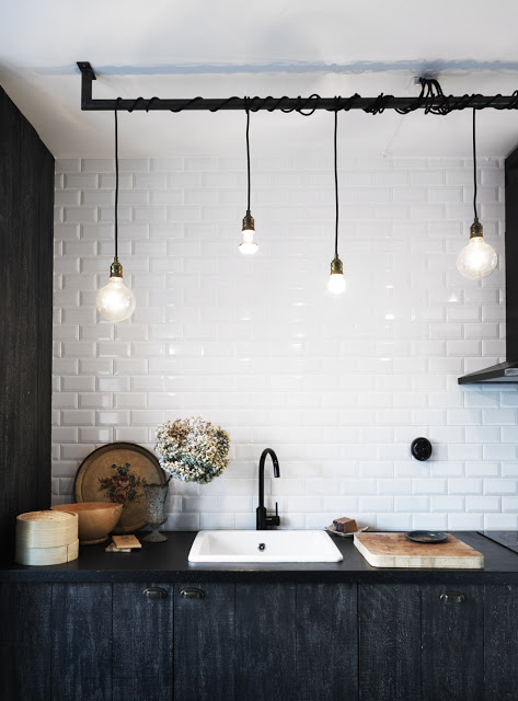 pendant lights over a sink with dark wood cabinets and counter
