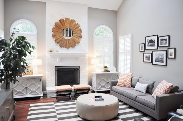 family room with grey walls, a grey and white striped rug, a white painted brick fireplace and a round ottoman