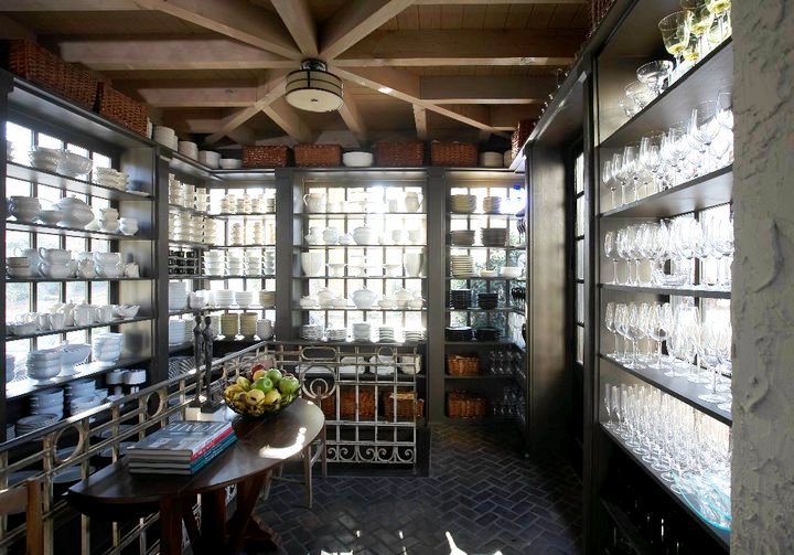 Butler's pantry with herringbone brick floor, exposed beams and open shelving light from behind