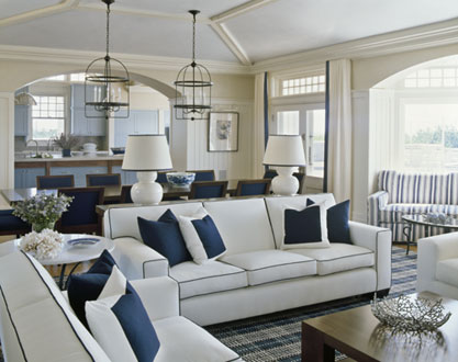 Nautical living room with a blue and white striped sofa, white curtains with a single blue strip where they meet, pendant lights and two white sofas with blue piping