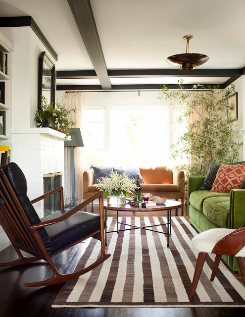 Living room with a striped rug, green sofa and exposed ceiling beams