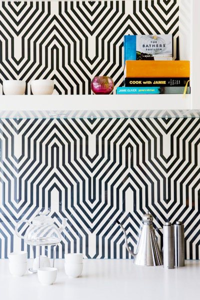 close up of kitchen with black and white geometric backsplash and white floating shelves