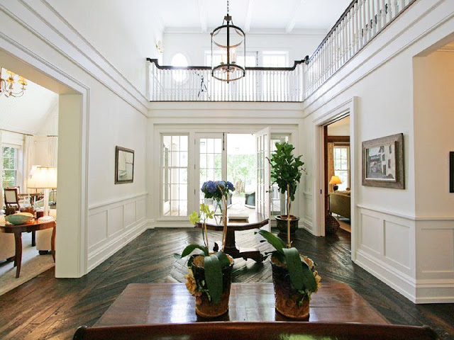 foyer with herringbone wood floors, french doors, double height entry and a large pendant light