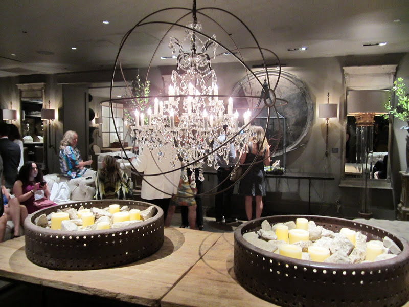 a reclaimed wood table under a crystal chandelier in a wire ball inside the new Restoration Hardware store in Los Angeles