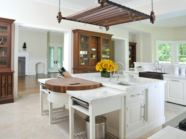 white kitchen with farmhouse sink, island and wood cabinets and hanging pot rack