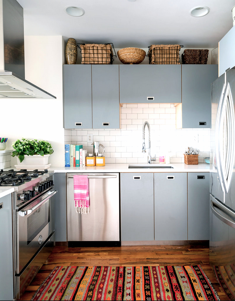 Kitchen in Anne Maxwell's colorful NYC loft apartment with powder blue flat doors, Caesarestone counters, and a Peruvian rug