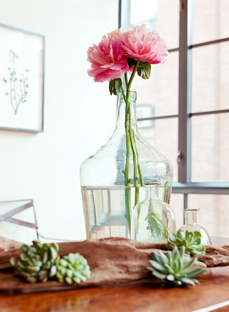Close up of dining room centerpiece with pink flower, succulents, and reclaimed wood table