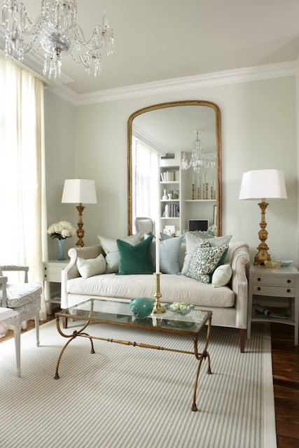 sarah richardson's living room with pale green sea green accents with gold coffee table, brass lamps arched curved gold mirror