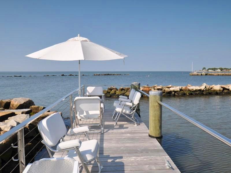 Private dock with metal chairs with white cushions and a large white umbrella