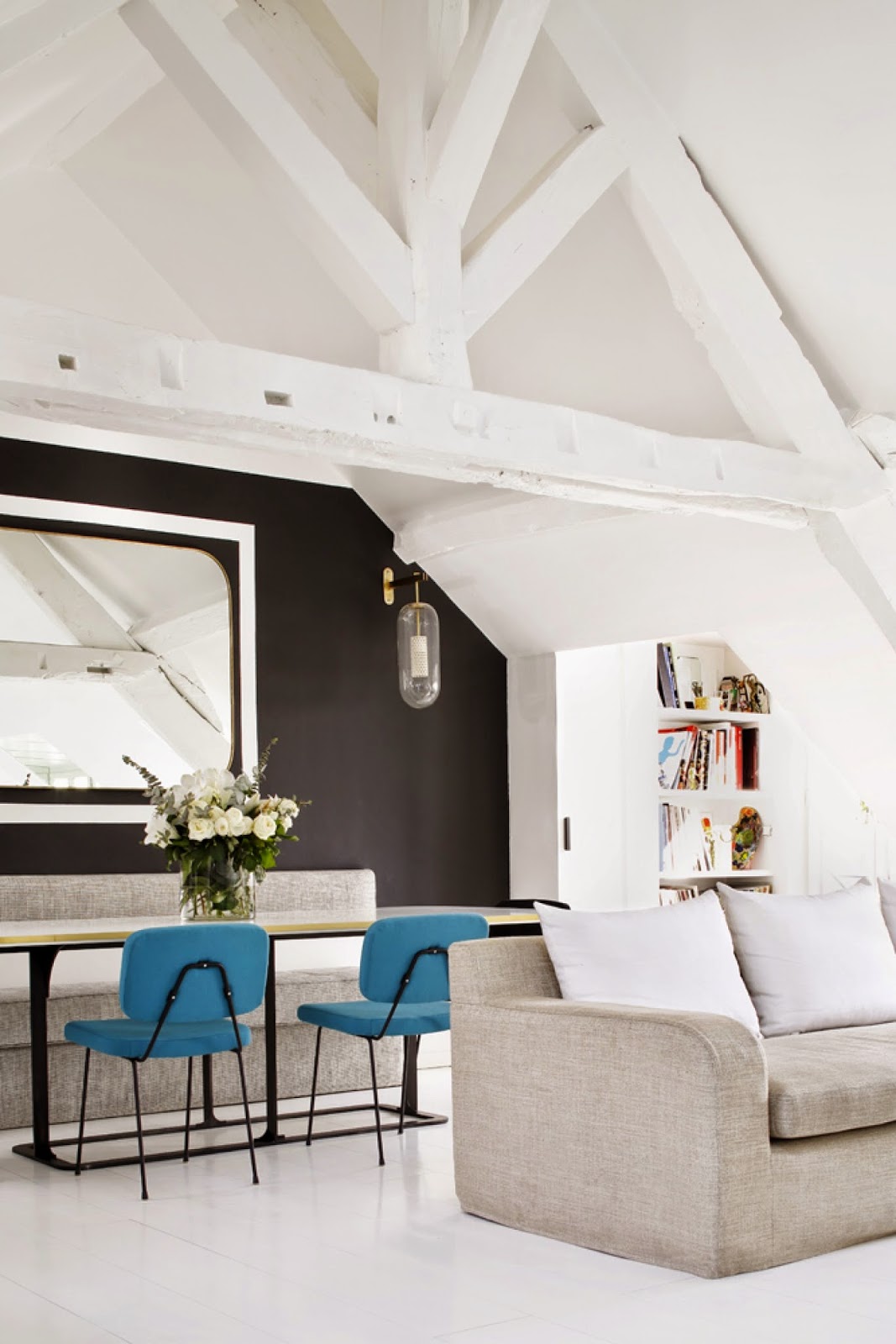 Open plan living room in a Paris attic apartment with black accent wall