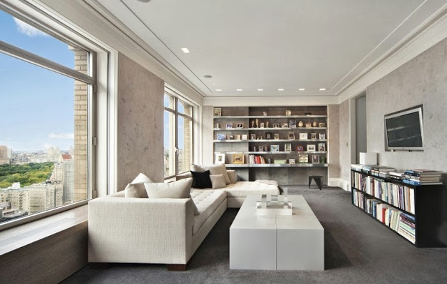 Media room in a NYC penthouse with white sectional sofa and ottoman