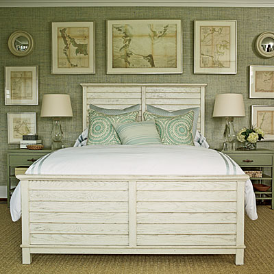 Master bedroom with sea grass aqua wallpaper, framed nautical prints on the wall behind the large wood bed with two matching night stands and a sea grass area rug on a wood floor