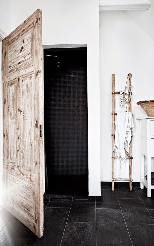 White bathroom with rustic wood door and black tile floor in Jenny Hjalmarsson Boldsen's home