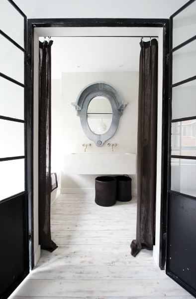 Bathroom with painted white wood floors, glass interior doors, dark sheer curtains, a metal mirror, and a large basin porcelain sink