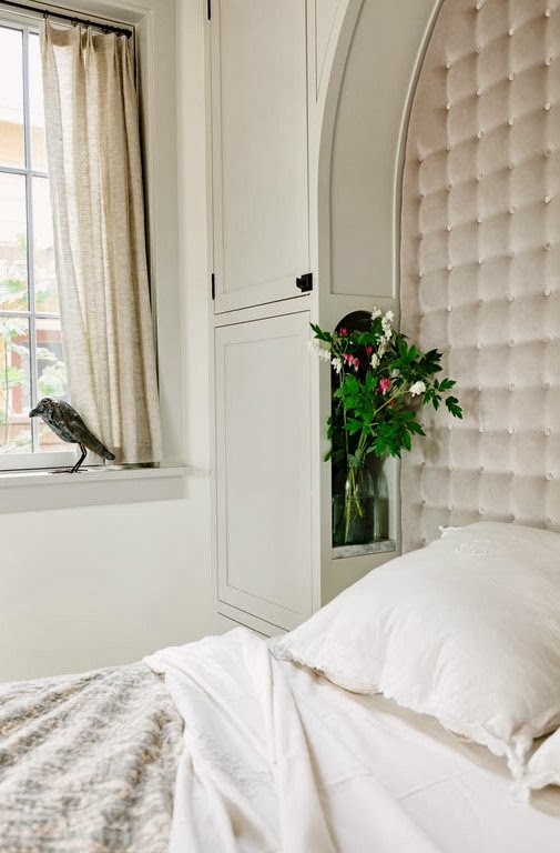 White bedroom with built in tufted headboard and fresh flowers