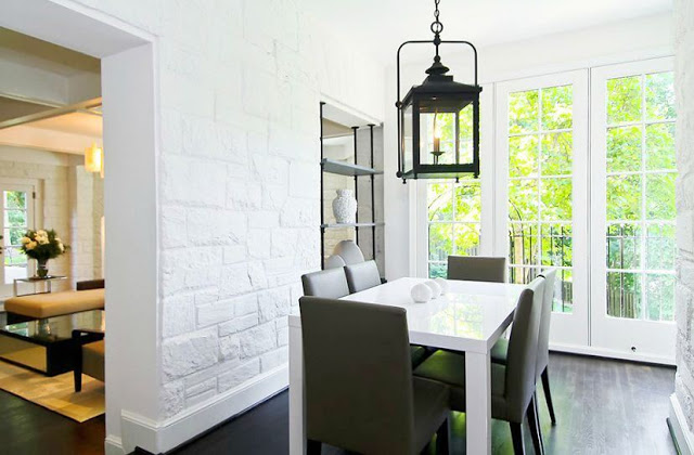 Breakfast nook with white stone walls, Parsons white lacquer table, french doors and a black lantern style pendant light