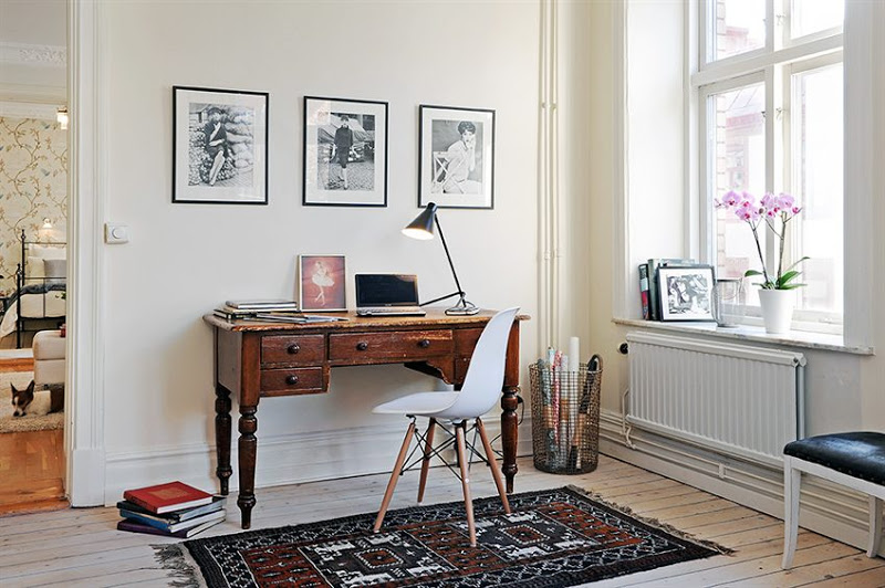 Home office in a Swedish apartment with knotty light wood floor, Eames chair, vintage desk and three framed sketches