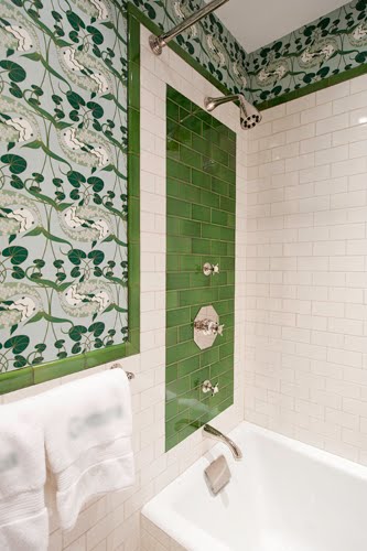 Bathroom with green and white subway tile on the walls with art deco inspired tiling on the border 