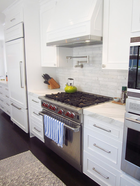 close up of stainless steel appliance oven with stove and white panel hood