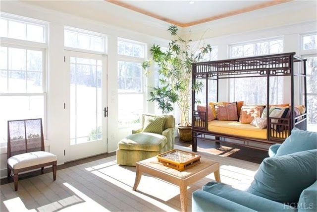 Bright sunroom with wood floor, green armchair and blue sofa in a Bedford, NY home