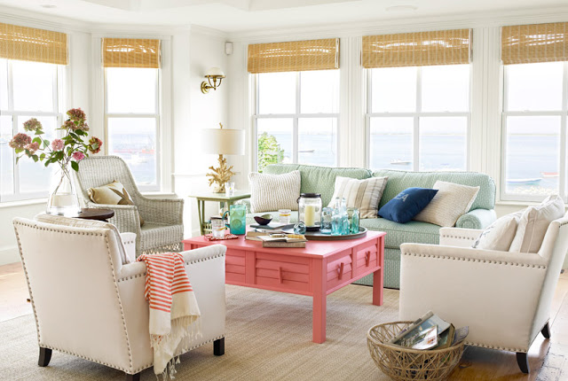 costal living room with many windows, a pink coffee table, three upholstered  cream colored armchairs and a mint green sofa