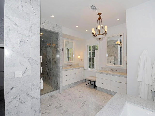 Master bathroom with marble floor, wall and counter tops, white drawers and a pendant light 