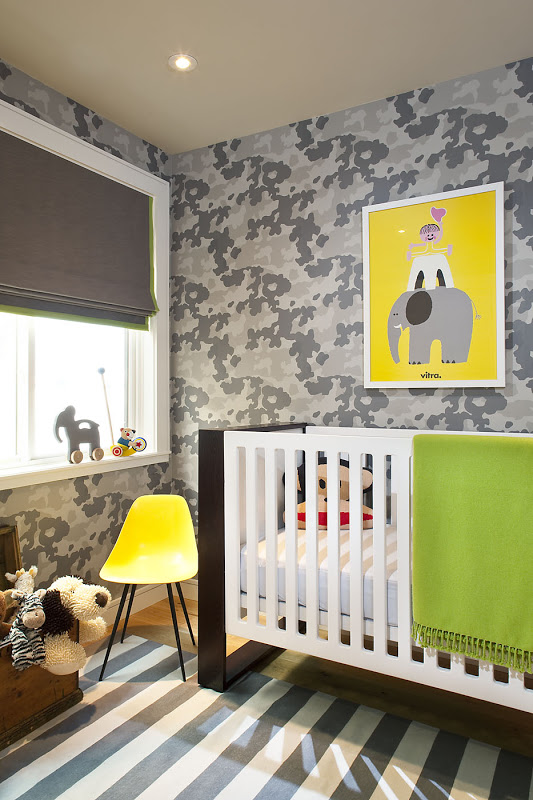 Baby room with floor to ceiling grey wallpaper, a blue and white striped rug, roman shades, a yellow Eames chair, a graphic dark wood and white crib and a bright picture of child riding an elephant with a yellow background