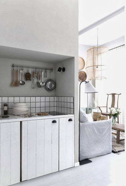 Small white kitchen in a French apartment with black grout and white paneled cabinet doors with black pulls