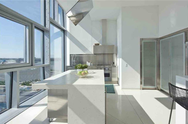 Sleek, modern kitchen with stainless appliances and cabinets. The island has a stainless base with a white counter top