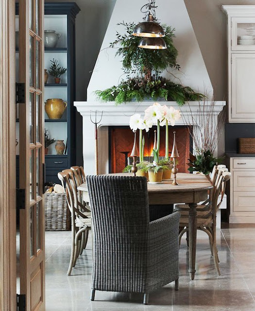 michael graydon's rustic dining room with wicker host chair and green holiday garland over a large white fireplace