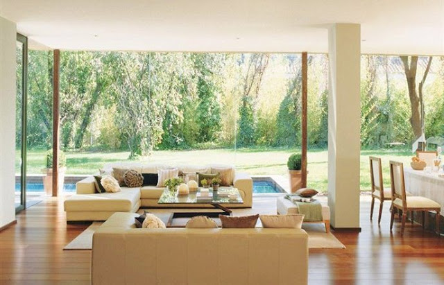 Living room with glass walls, wood floor and dueling sofas in Spain